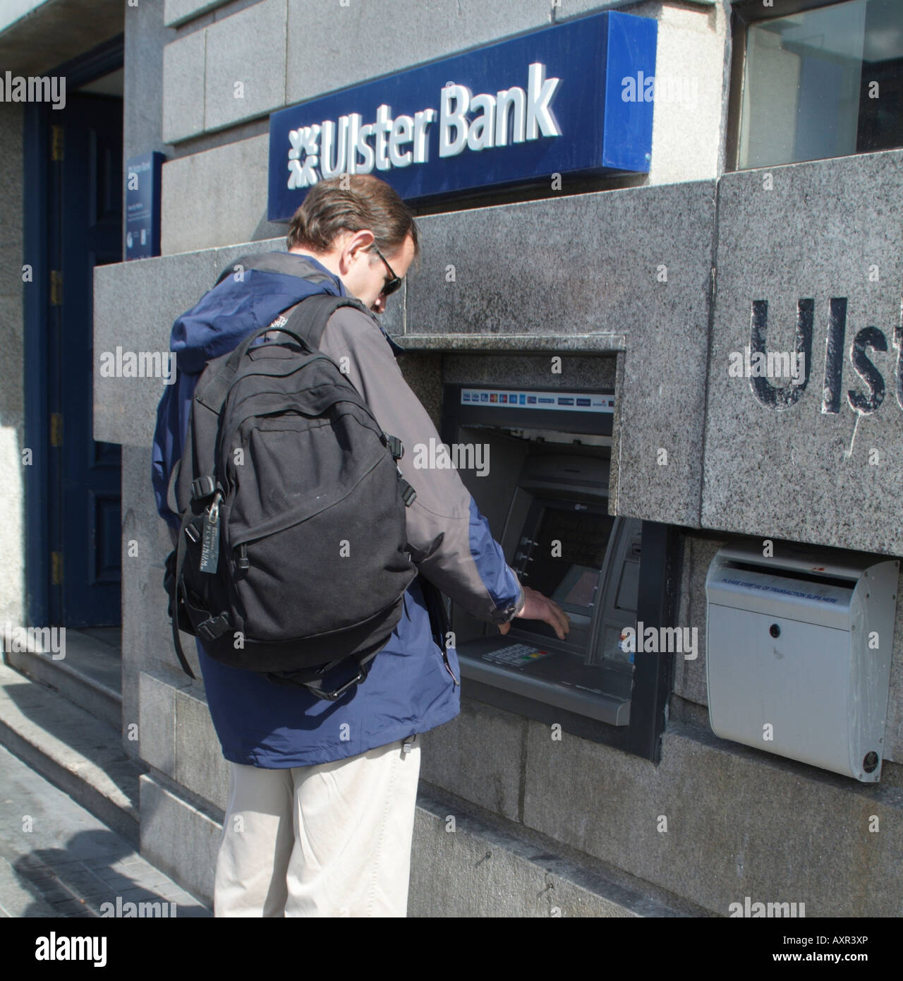 Man Using Hole in the Wall Cash Dispenser Machine at Ulster bank in Dublin Stock Photo