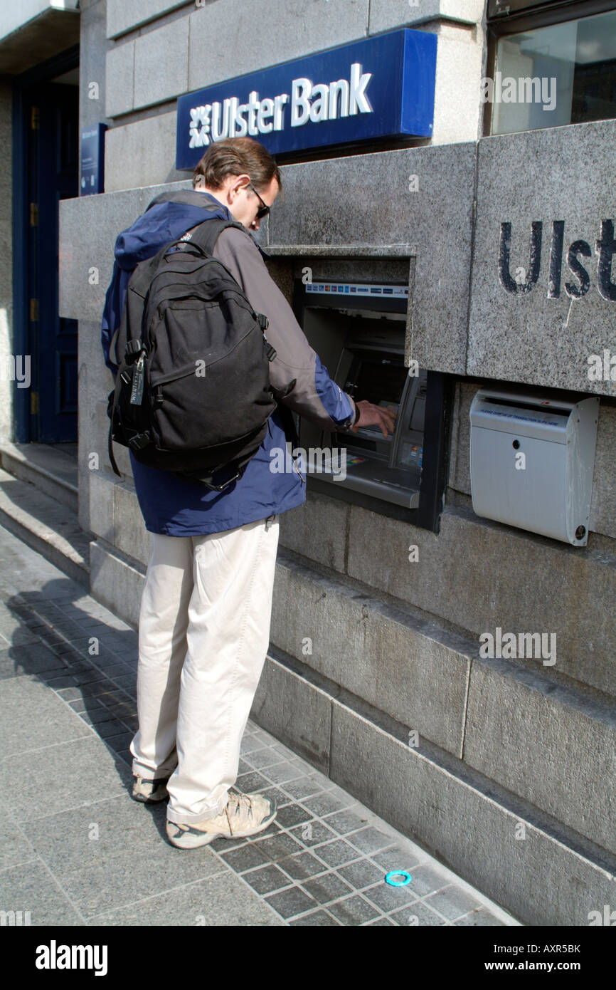 Man Using Hole in the Wall Cash Dispenser Machine at Ulster bank in Dublin Stock Photo