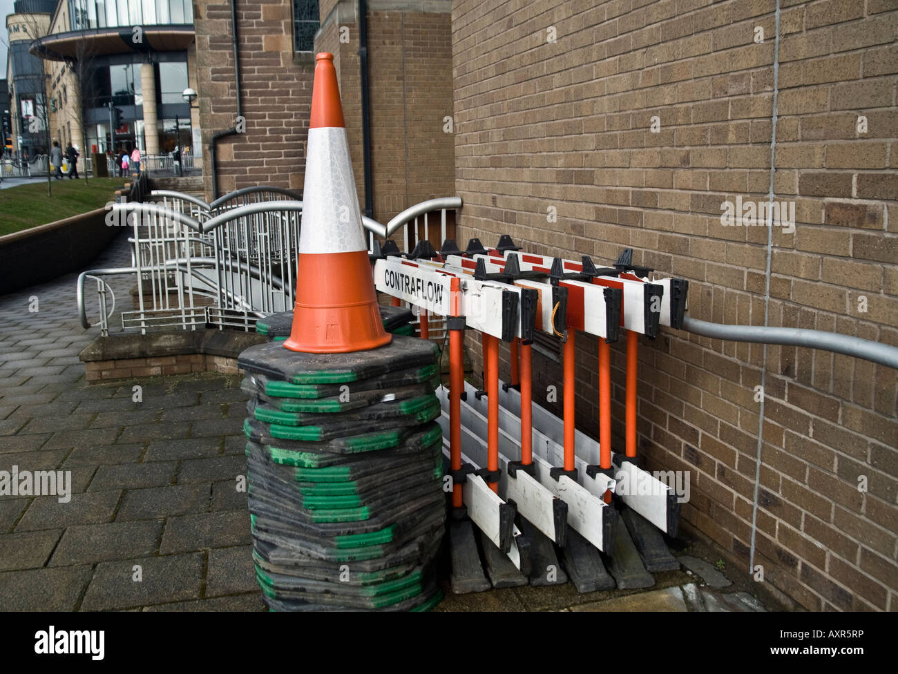 PVC fluorescent contra flow road cones and barriers piled on sidewalk against a building wall in Dundee,UK Stock Photo