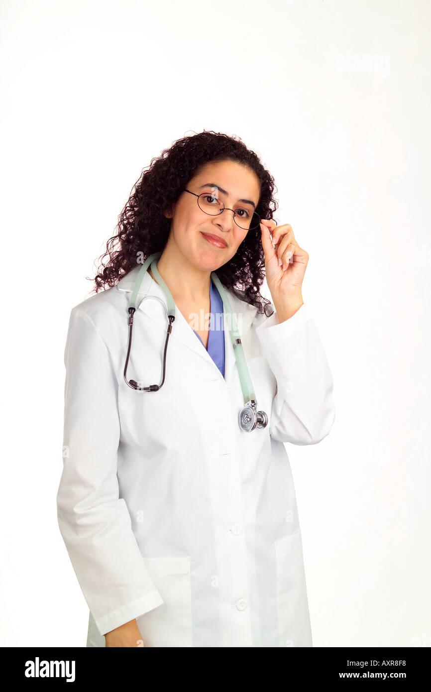Woman nurse or doctor with long dark hair stands wearing a white lab coat stethoscope and glasses  Stock Photo