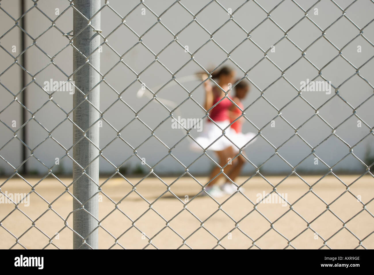 Girls skipping beyond a fence Stock Photo