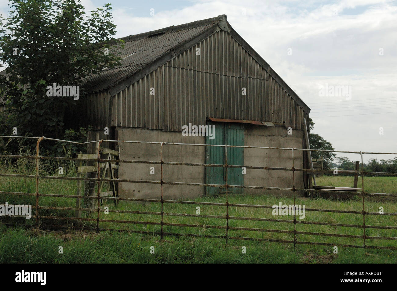 behind a rusting iron fence is an old barn with corrugated steel sides ...