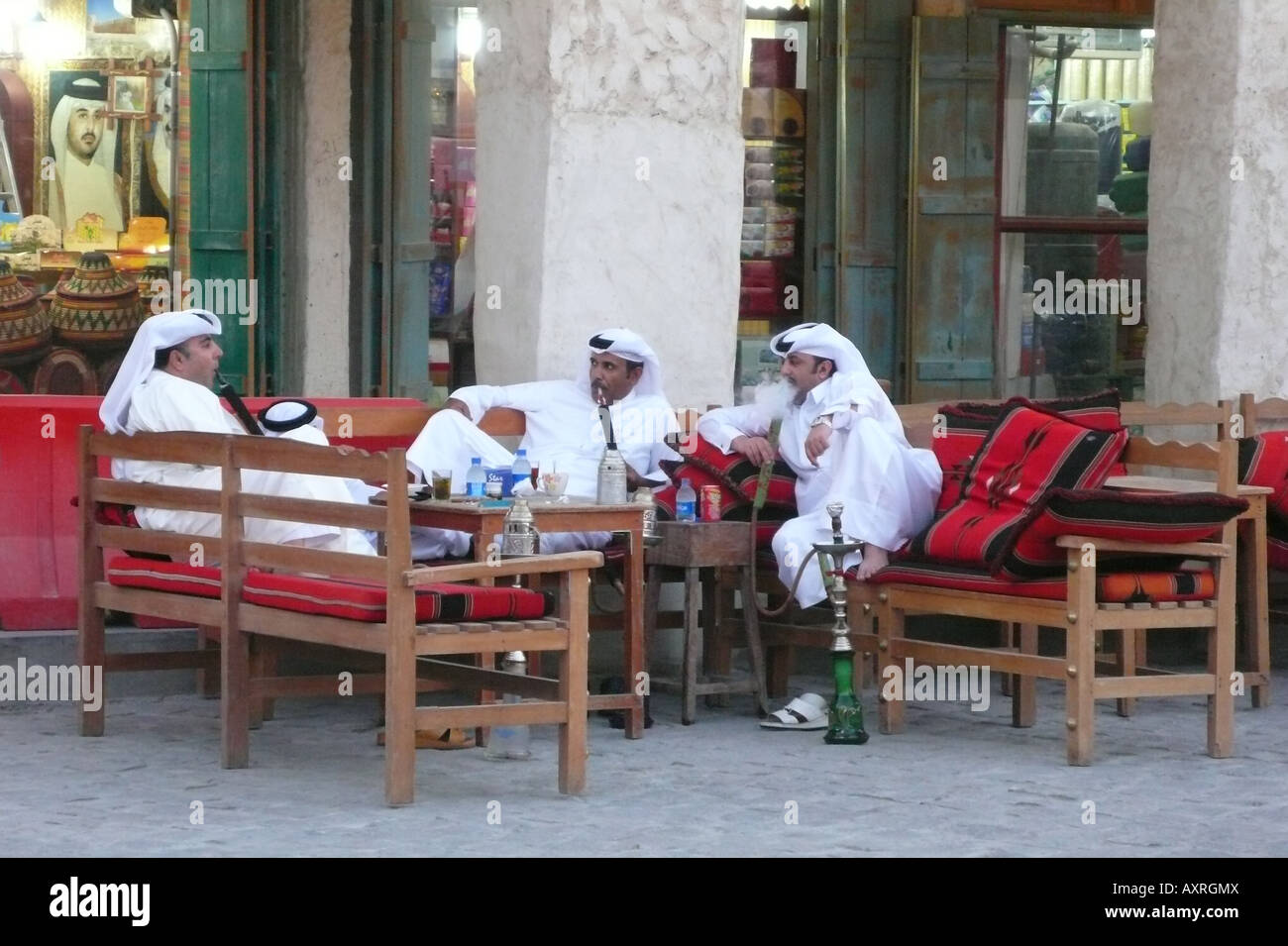 Three local men men sitting and smoking shisha outside a shop at Souq