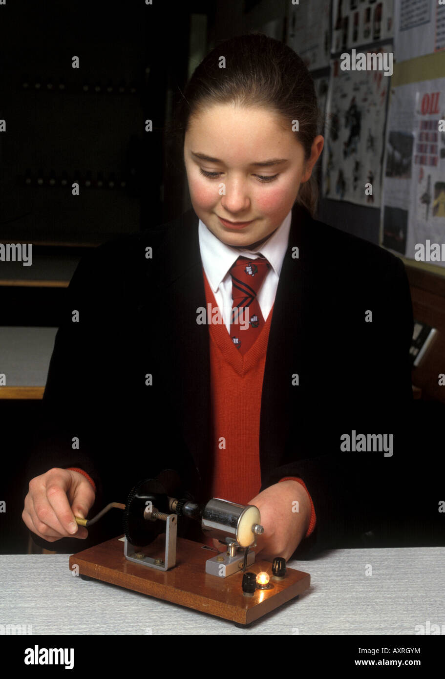 schoolgirl hand cranks a dynamo generating electricity to light a bulb Stock Photo