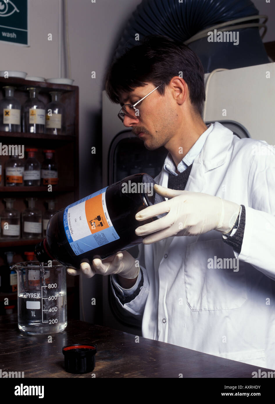 Lab technician pours concentrated hydrochloric acid into water never the other way round Stock Photo