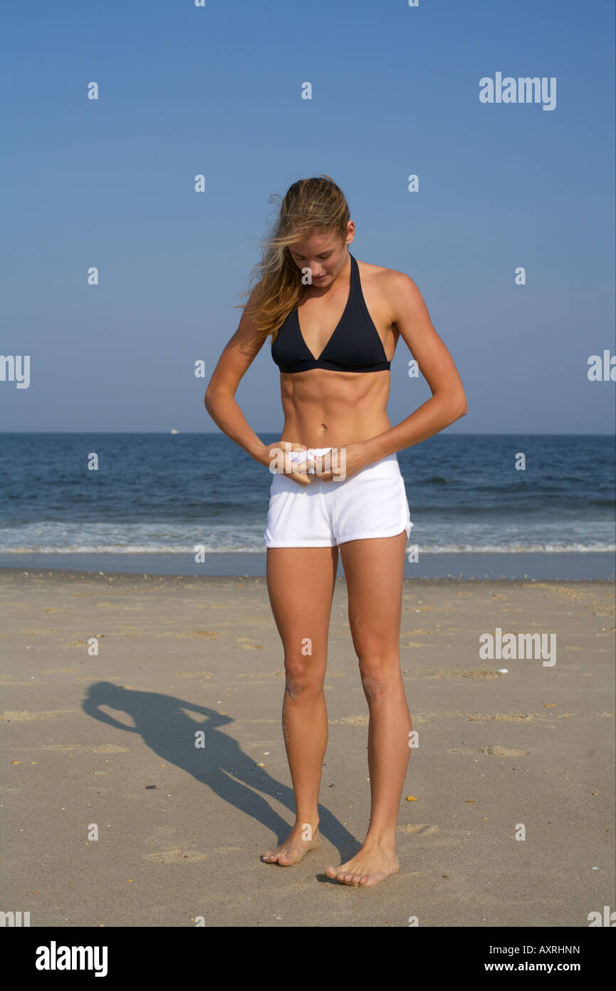 Young blond woman putting on pants at the beach Stock Photo Alamy