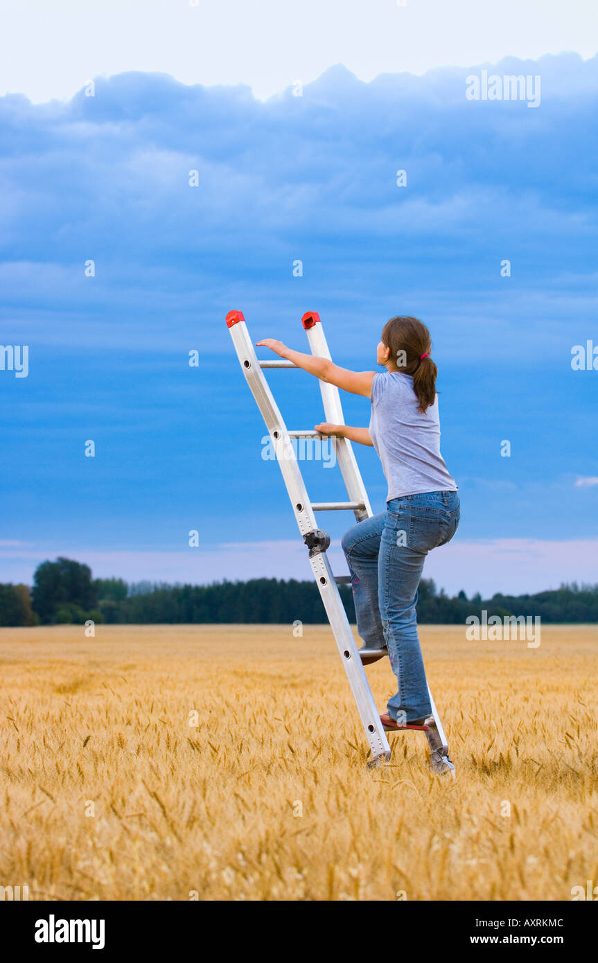 Young woman climbing ladder to the sky Stock Photo Alamy