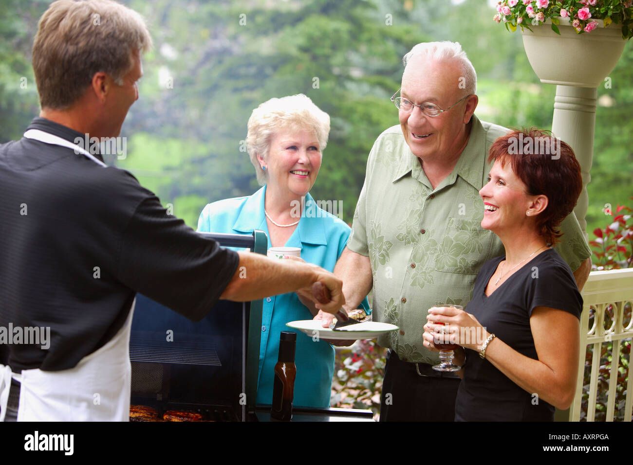 Man barbecuing and serving burgers Stock Photo