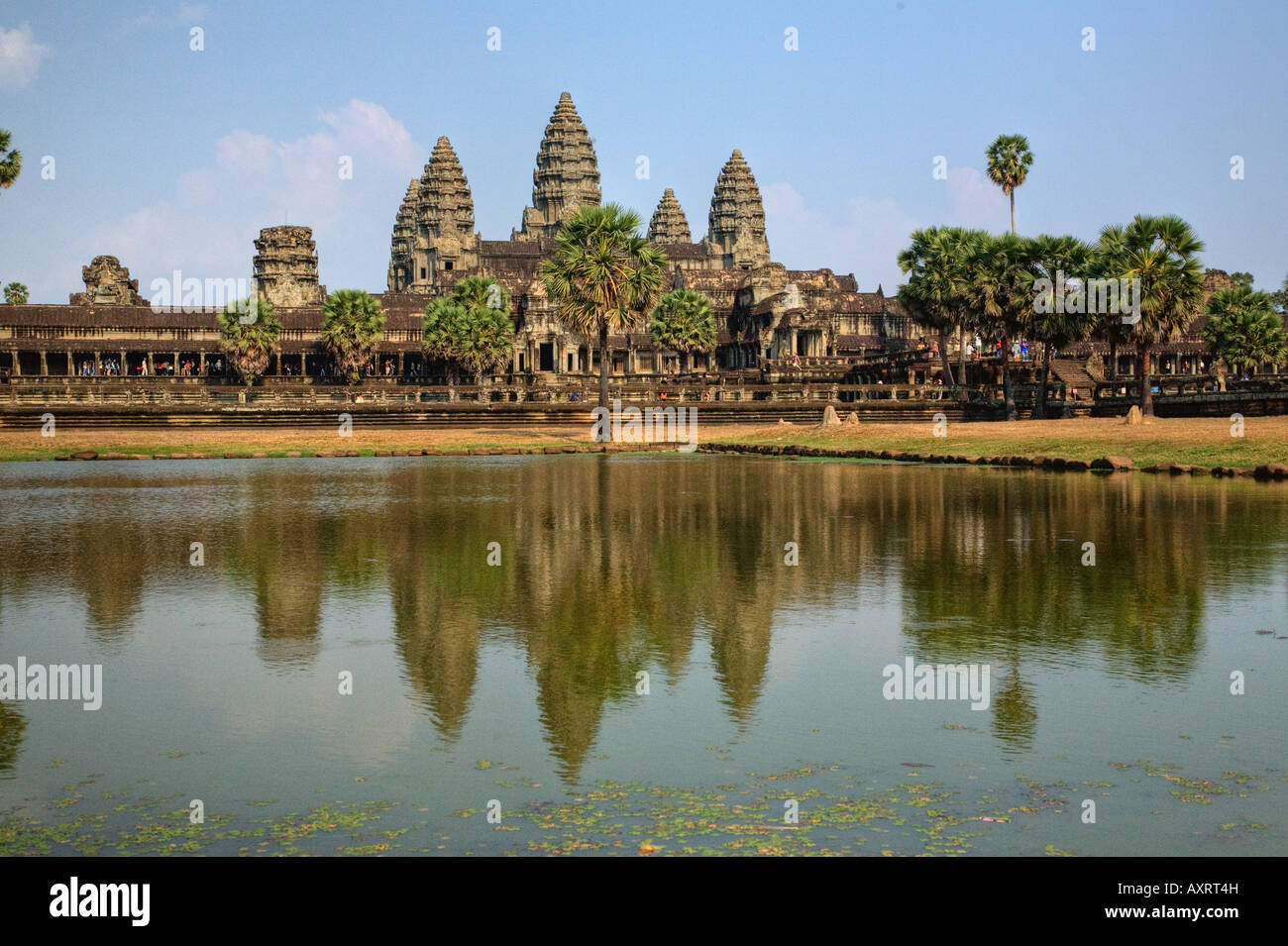 The pool at Angkor Wat reflects the temple's 5 towers and palm trees ...