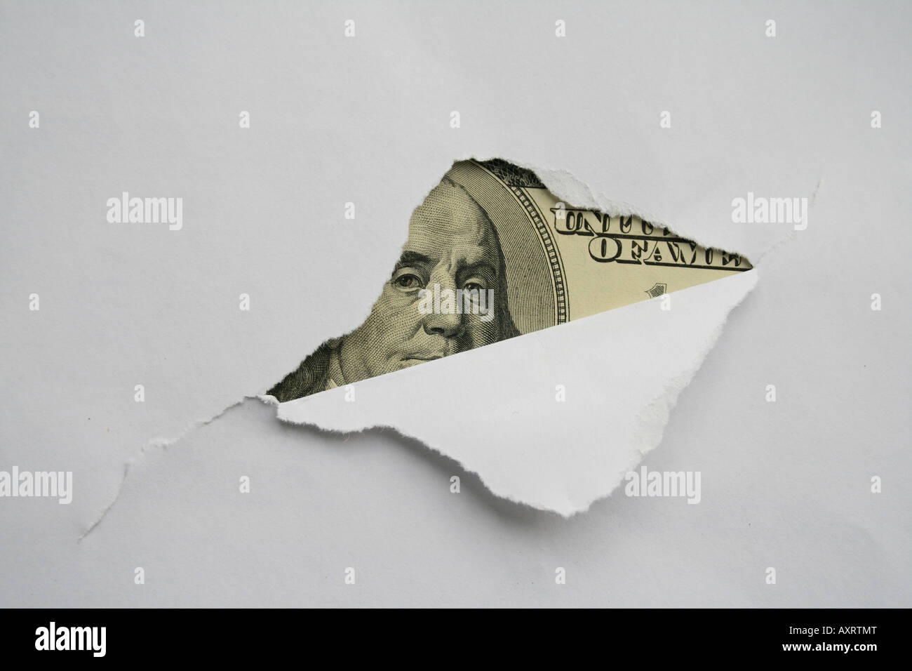 Large hole in the white paper and one hundred dollar bill in it. Stock Photo