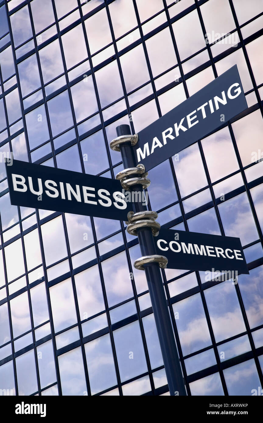 Concept image of a signpost with Business Marketing and Commerce against a modern glass office building with sky reflection Stock Photo