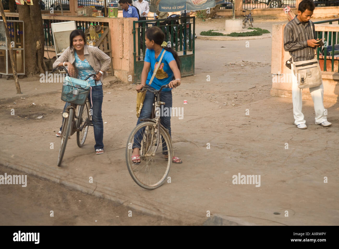 2 Cambodian girls on bicycles take a break from the daily commute Stock Photo