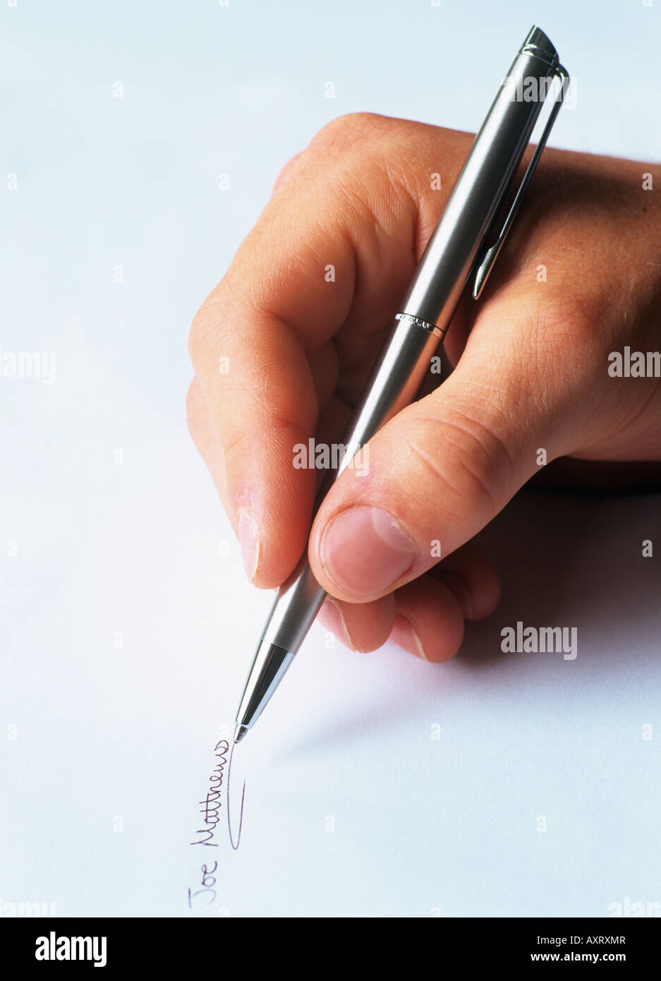 MAN'S HAND WRITING a SIGNATURE on a piece of paper with a silver ballpoint pen signing a document. England UK Britain Stock Photo