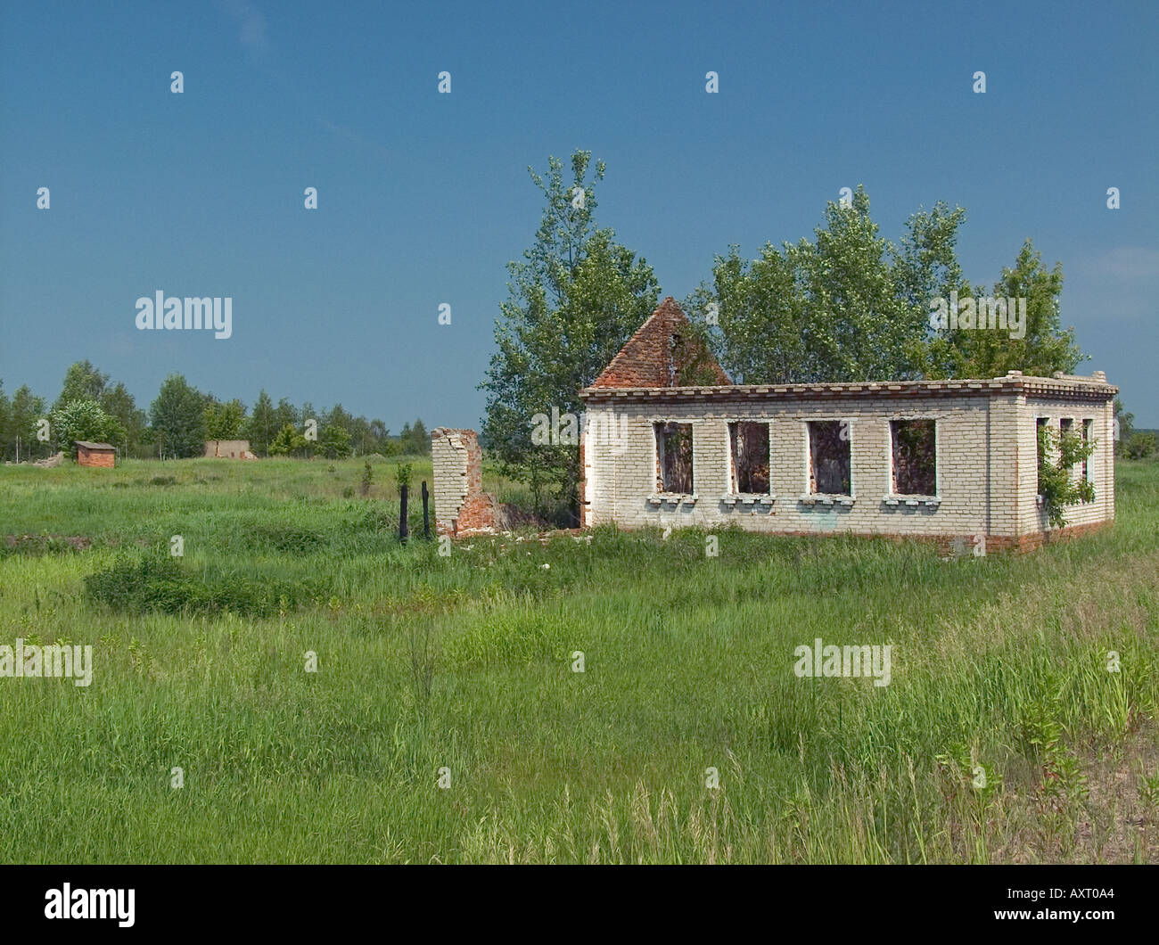 Derelict property with missing roof and distant outbuildings in lush pastoral landscape, Chernobyl exclusion zone, Belarus Ukraine state border Stock Photo