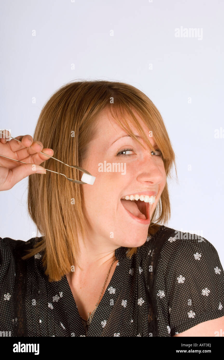 A happy young woman with sugar tongs and sugar cube. Stock Photo