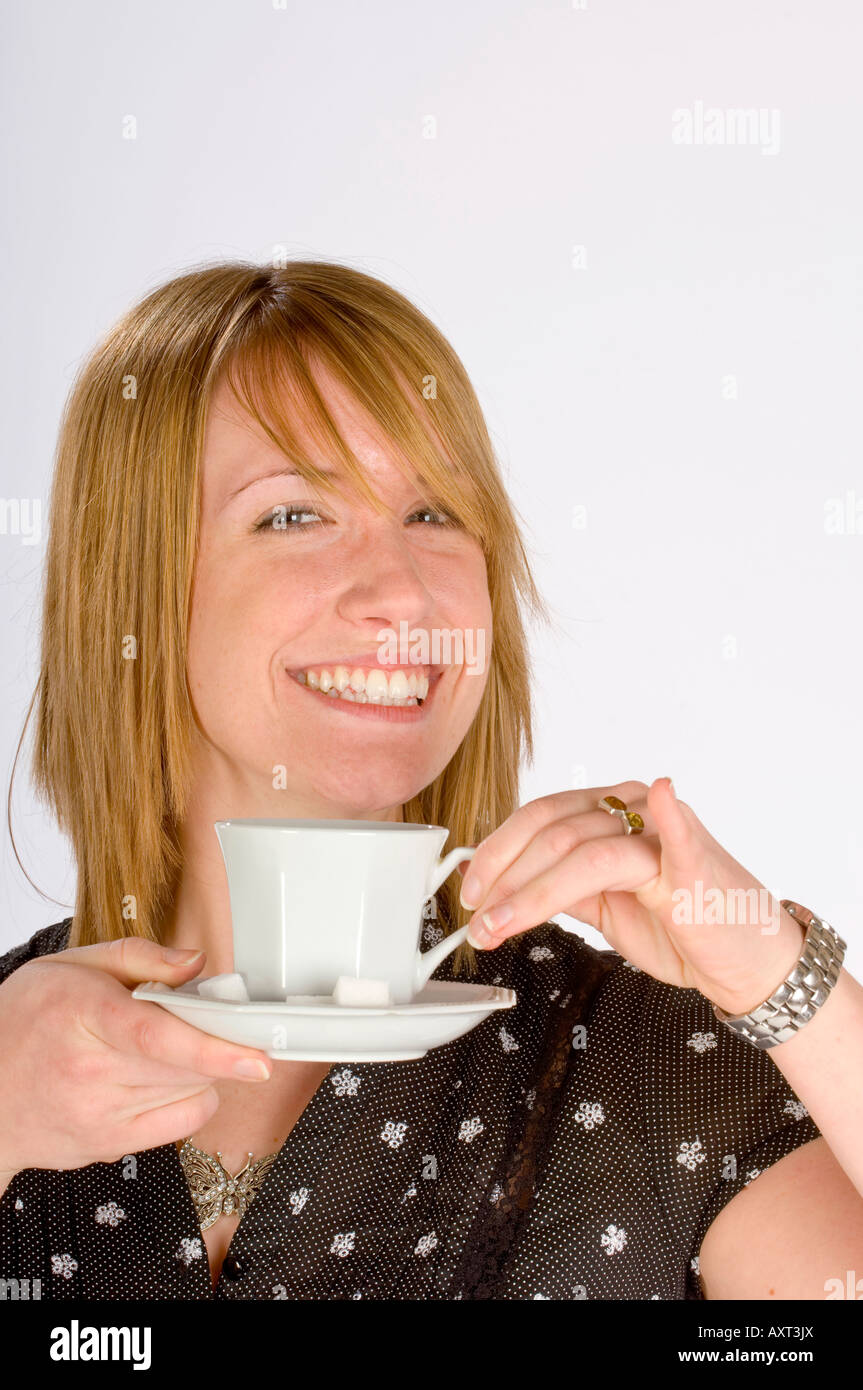 Sweet tooth: A smiling young woman puts less sugar in her tea. Picture by Jim Holden Stock Photo