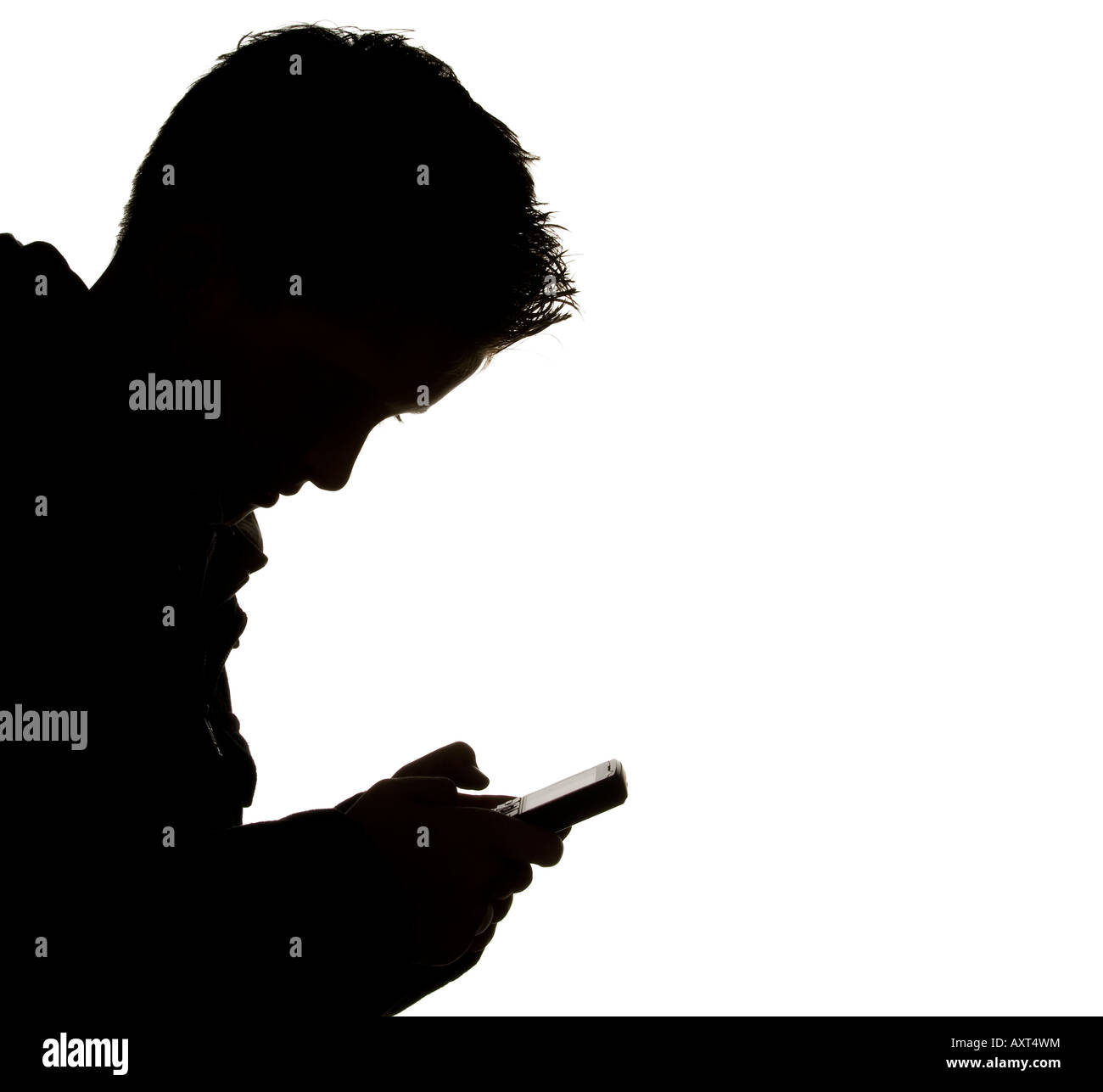 A silhouette of teenage boy text messaging with mobile phone, Picture by Jim Holden. Stock Photo