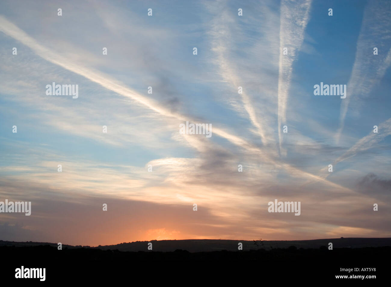 Aircraft vapour trails across the sky. Transatlantic flights following the beacons over British coast. Sunset. Stock Photo