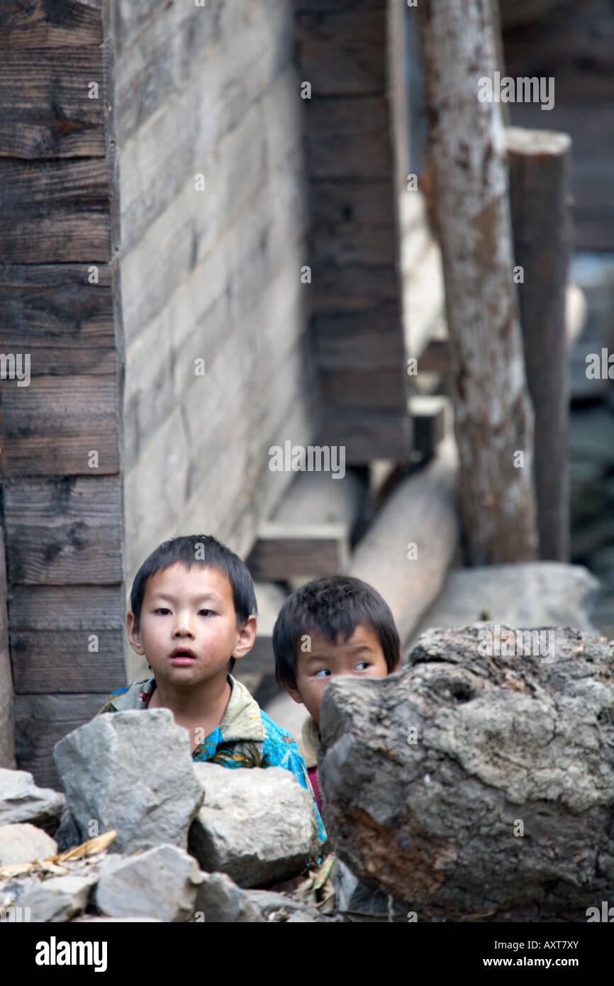 Children peeking over stone fence, Di Ma Luo, Yunnan, China Stock Photo