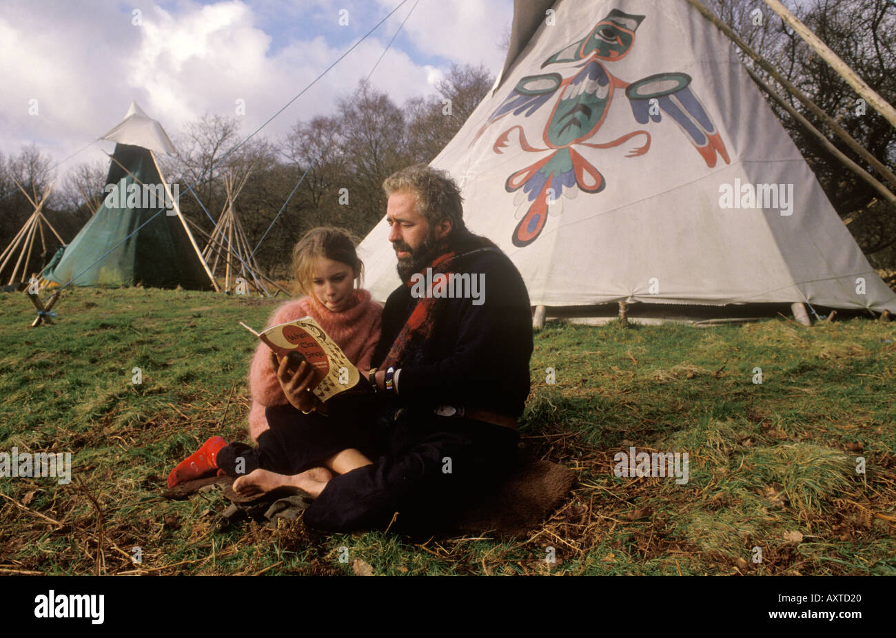 Tipi valley 1980s UK. Ged Edwards son Seren Edwards father reading a book. Dropping out of ordinary societ. 1985 Llandeilo, Wales 1985 HOMER SYKES Stock Photo