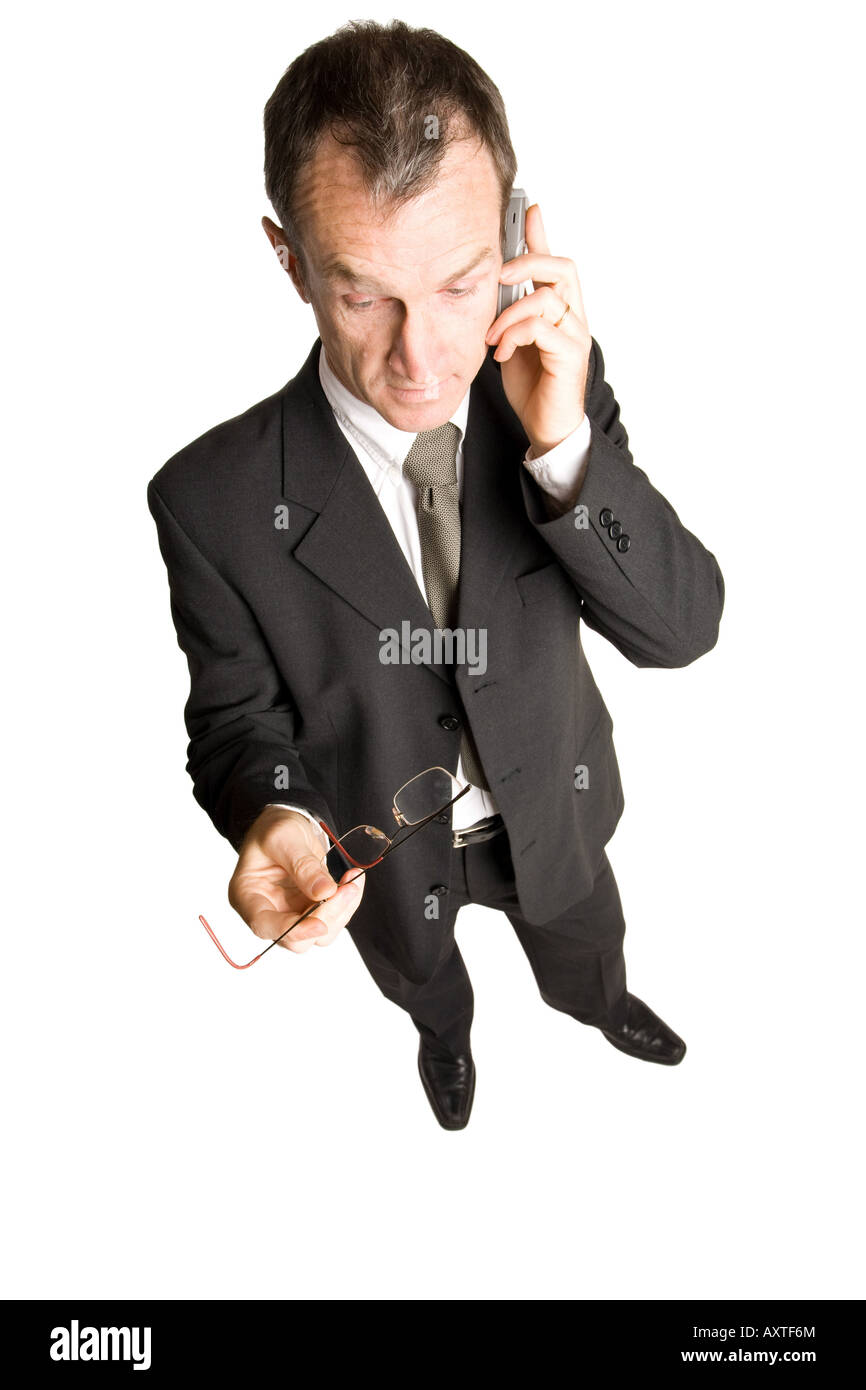 Business man standing in a black suit is talking on a mobile phone. The view is from the top-down he's holding glasses in hand and has a conversation. Stock Photo
