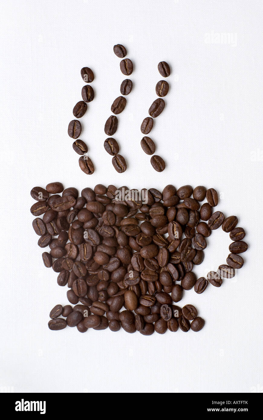 Coffee cup sign made of coffee seeds on the white table-cloth. Clipping path included. Stock Photo