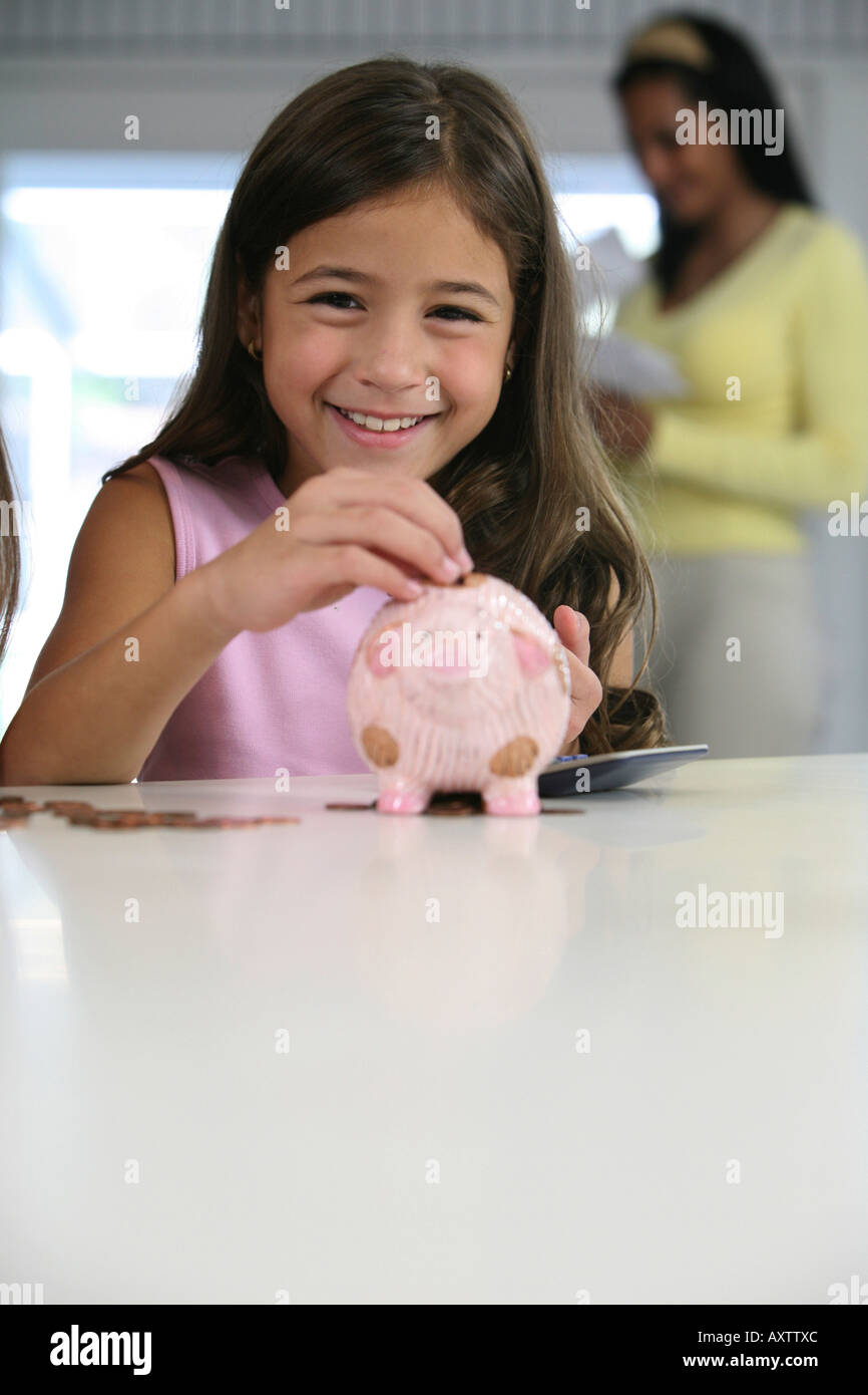 Portrait of a girl inserting coins into a piggy bank Stock Photo - Alamy
