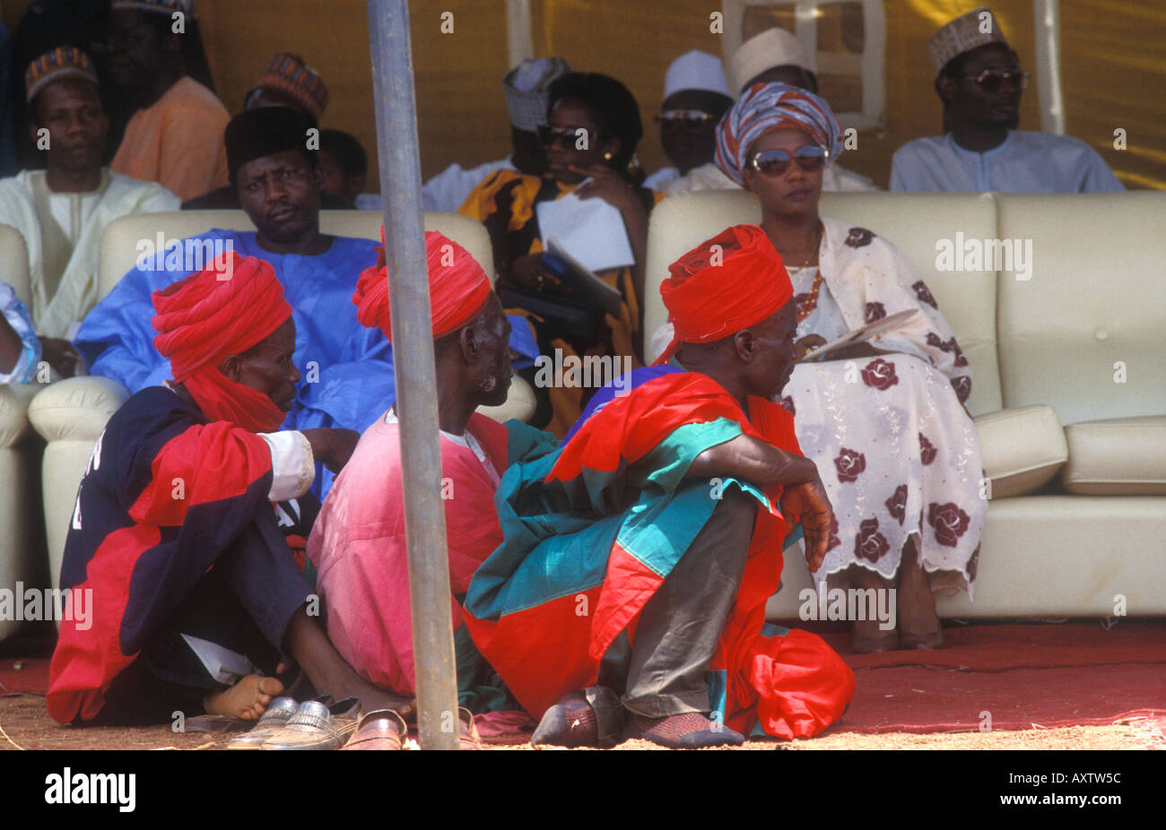 High ranking Nigerians watch performers at the Nok festival with their brightly robed guards sitting at their feet Stock Photo