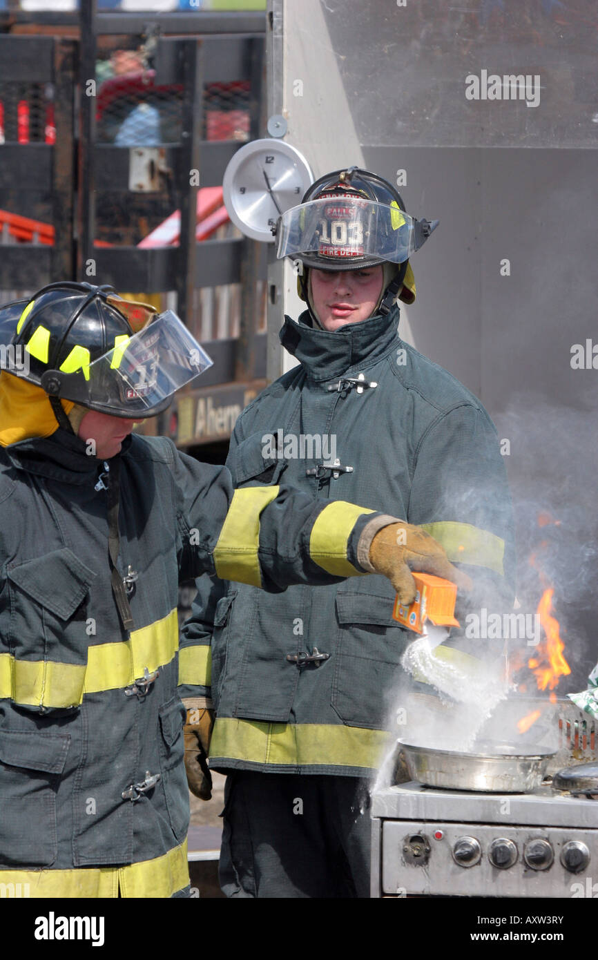 Two firefighters demonstrating how to extinguish a grease fire on the
