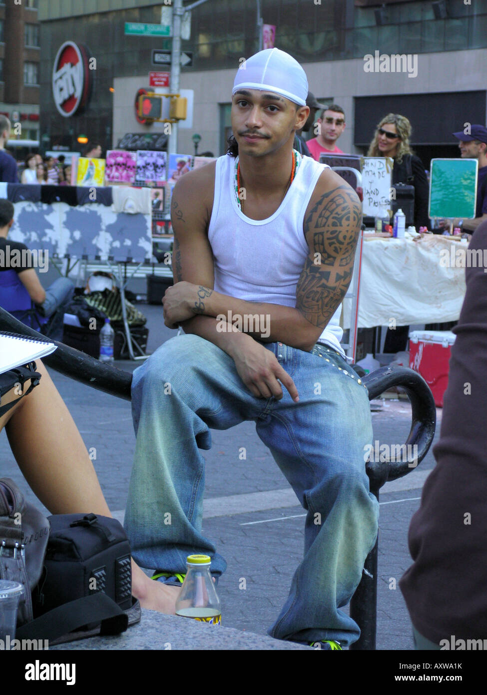 young man with conspicuous tatoo on his arm is sitting on a railing at Union Square, USA, Manhattan, New York Stock Photo