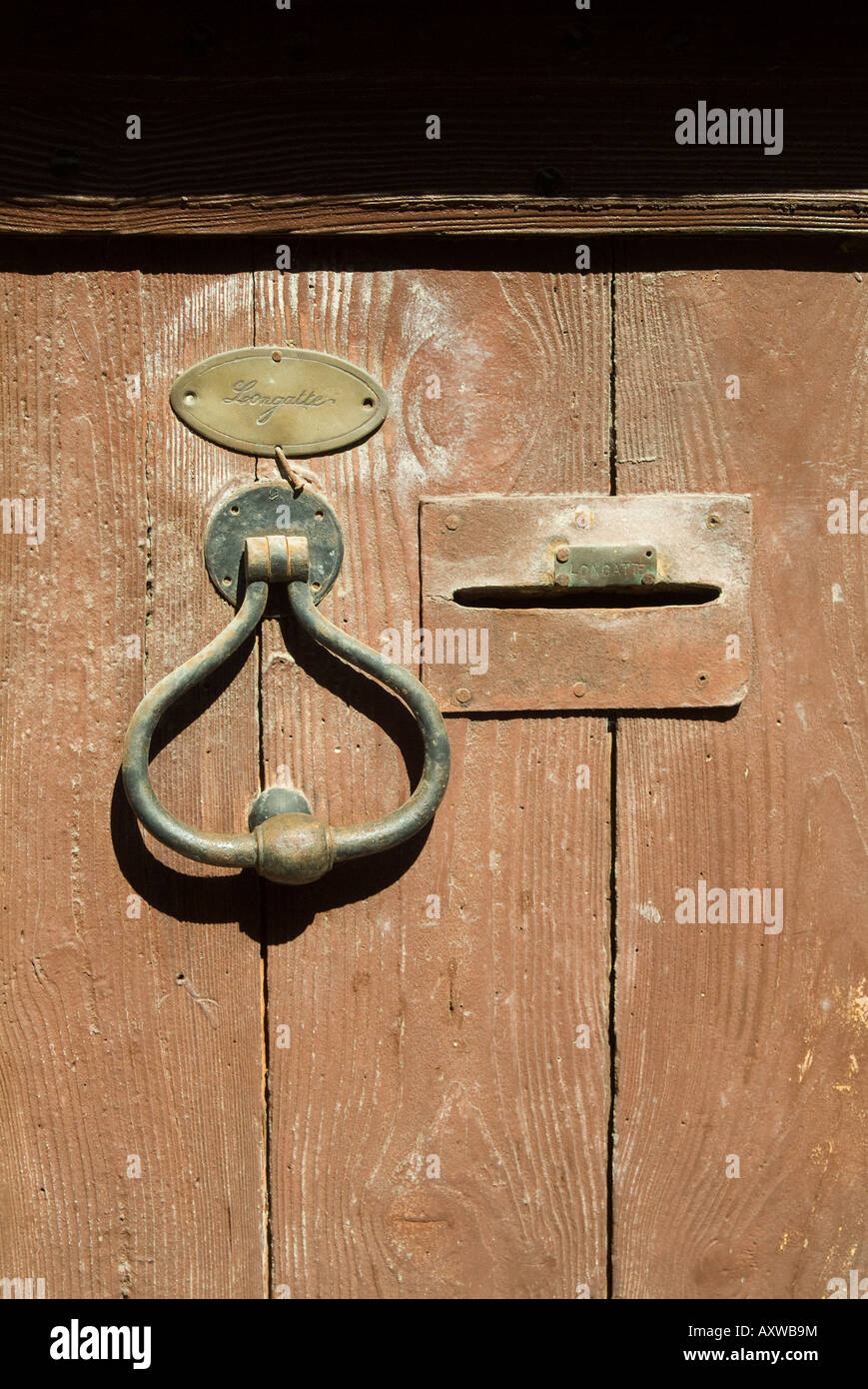 Old brass door knocker, name plate and letterbox on brown wooden door