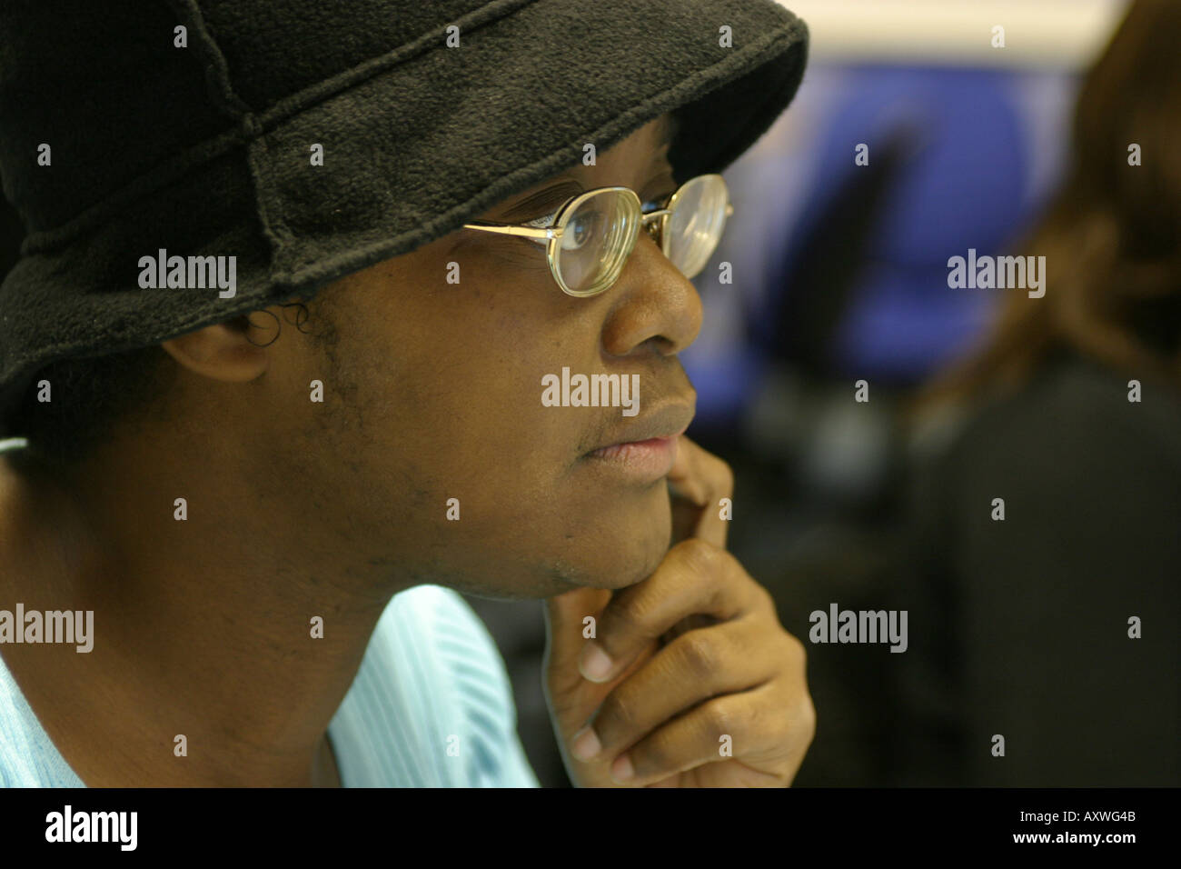 male student in class wearing hat and glasses looking studious Stock Photo