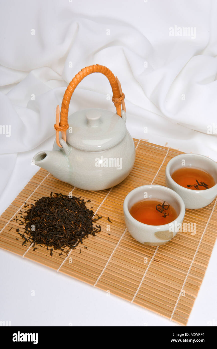 Green chinese teapot with tea cups and tea leaves ready to serve tea