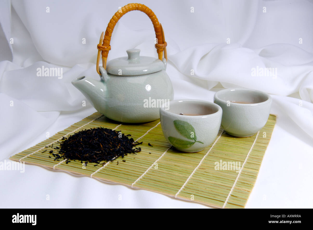 Green chinese teapot with tea cups and tea leaves ready to serve tea