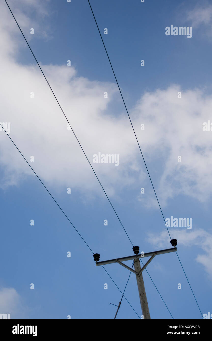 electricity pylon against a blue sky with a few puffy white clouds ...
