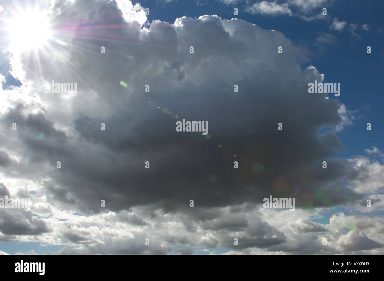 Large Cloud and Blue Sky and Sun Flare Stock Photo