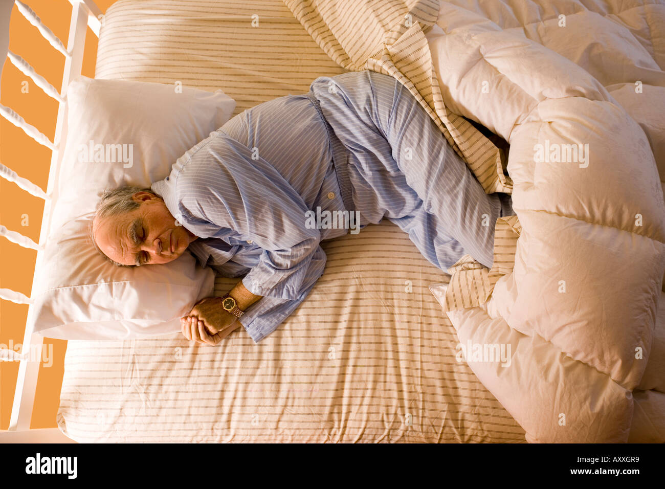 Man sleeping in the fetal position in his bed at home. Stock Photo