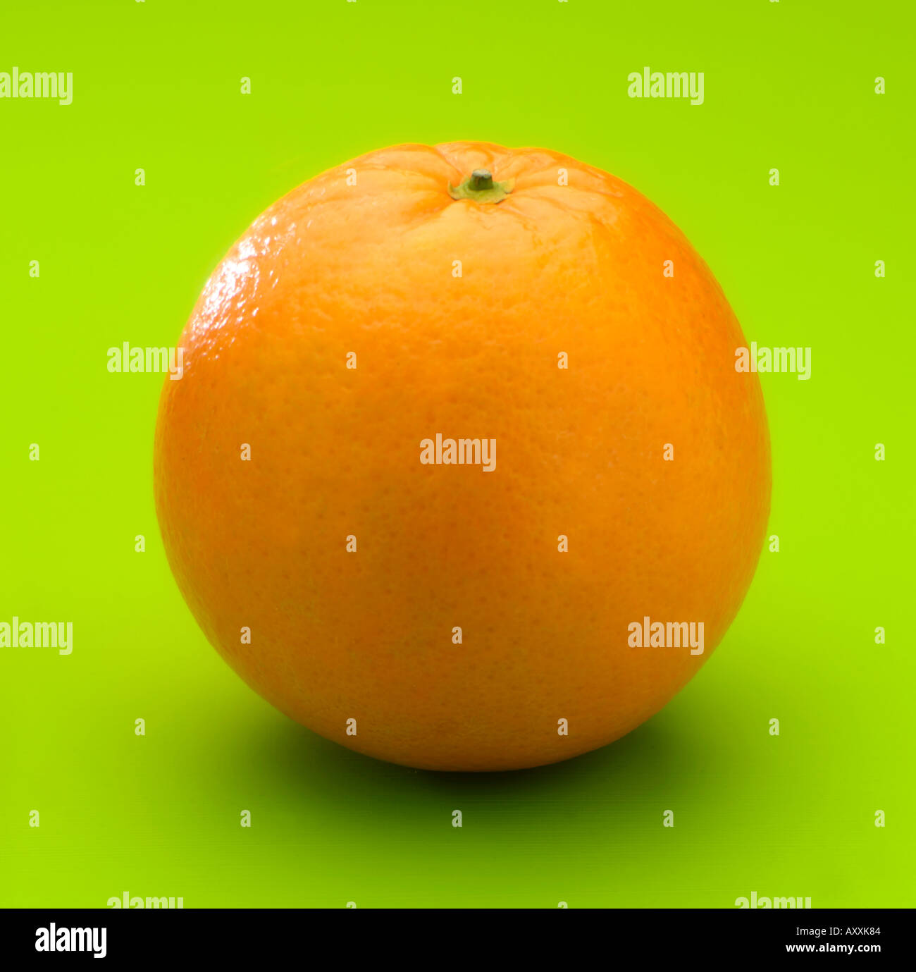 Single orange on green b g Stock Photo