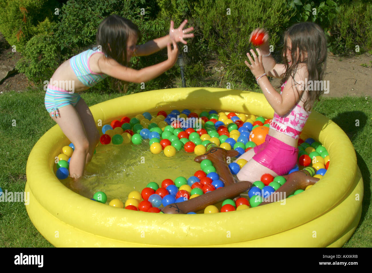Two young girls playing in paddling pool in garden Stock Photo 9676986