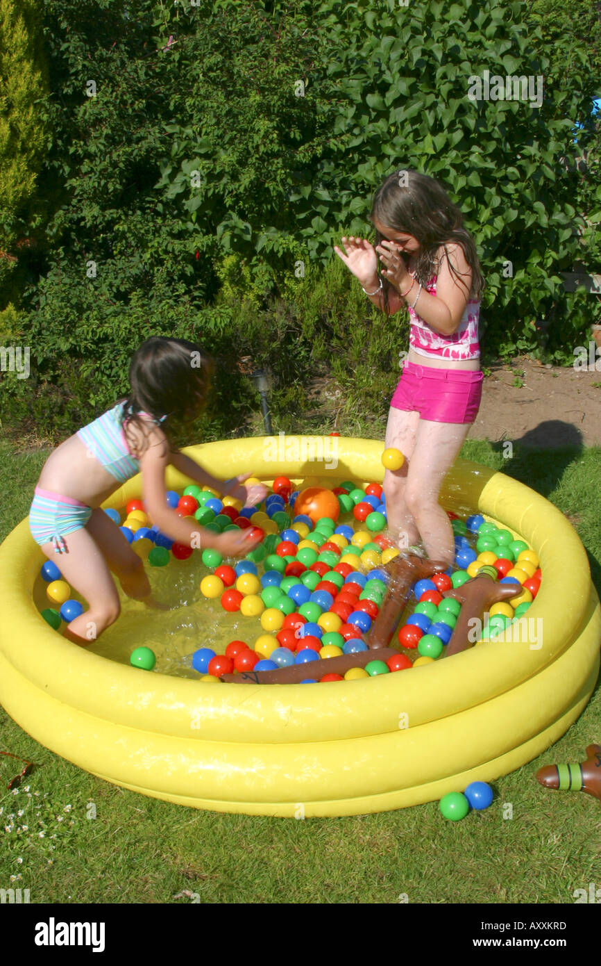 Two young girls playing in paddling pool in garden Stock Photo Alamy