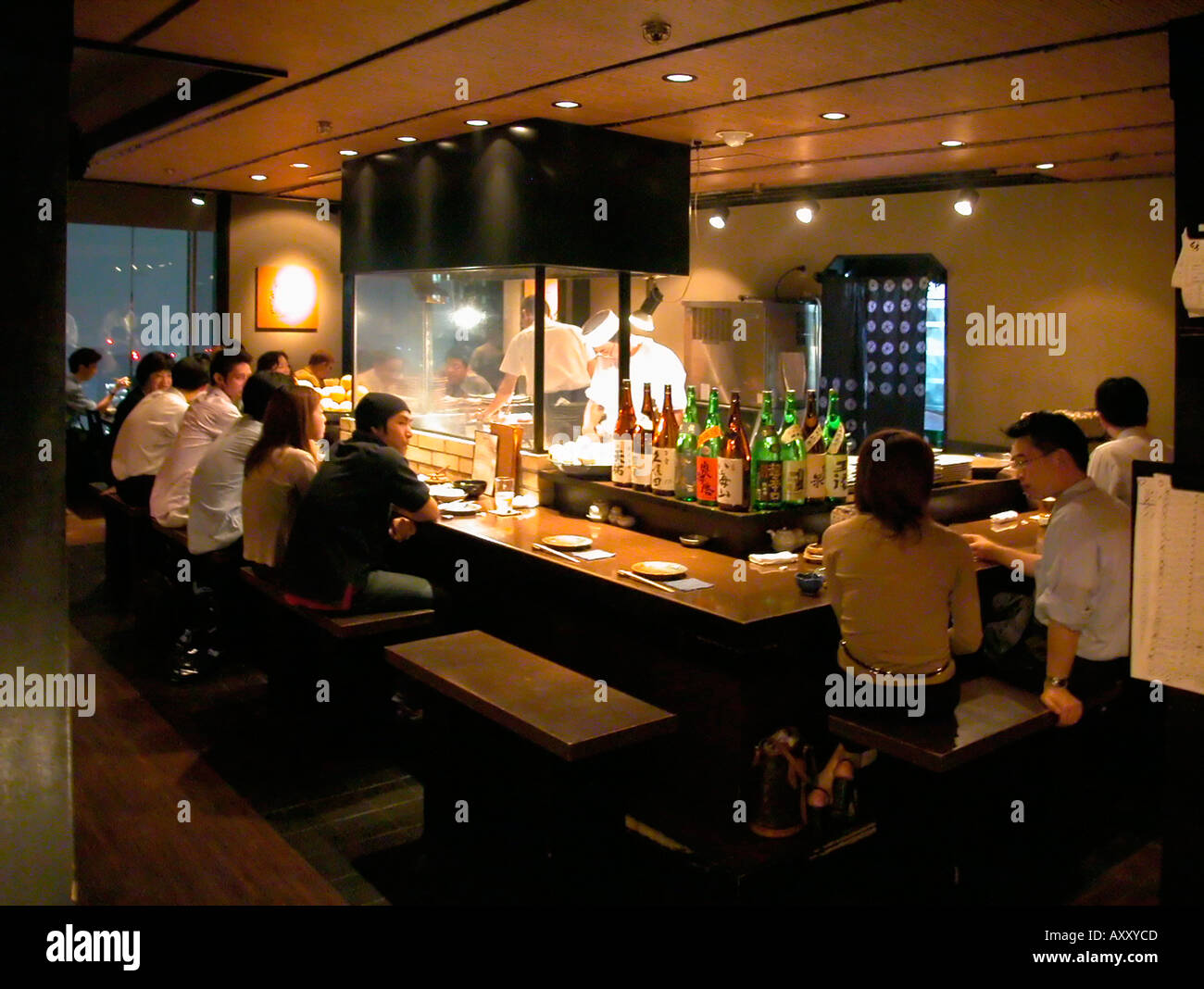Diners and Sake bottle display in Ku izakaya restaurant Shinjuku Tokyo Japan Stock Photo