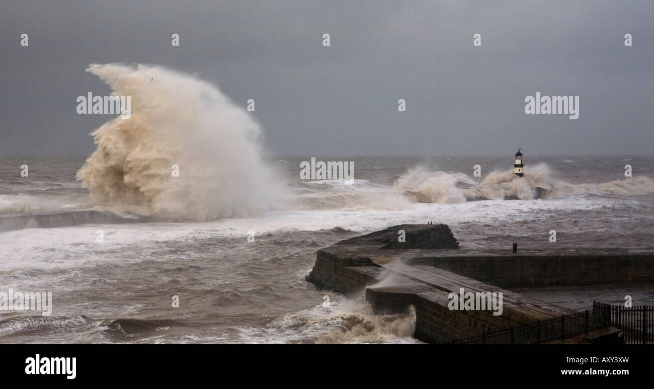 storm waves break over the sea wall & lighthouse at Seaham Pier in the UK Stock Photo