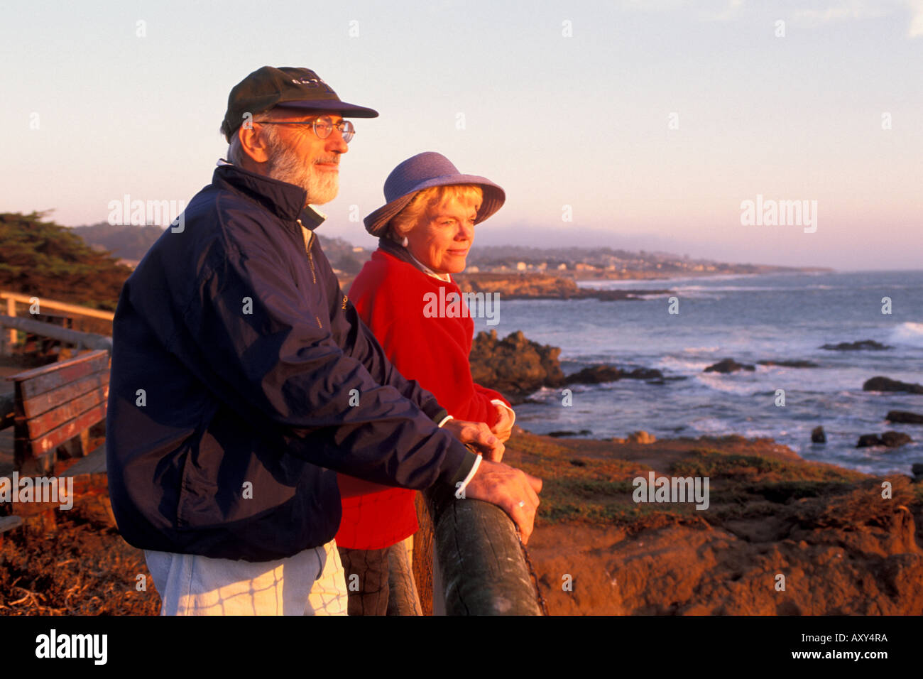 Mature adult tourist couple watching the sunset over Pacific Ocean from Leffingwell Landing Cambria California Stock Photo
