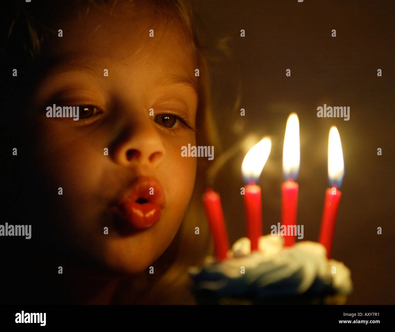 Child blowing out candles on her fourth birthday Stock Photo Alamy