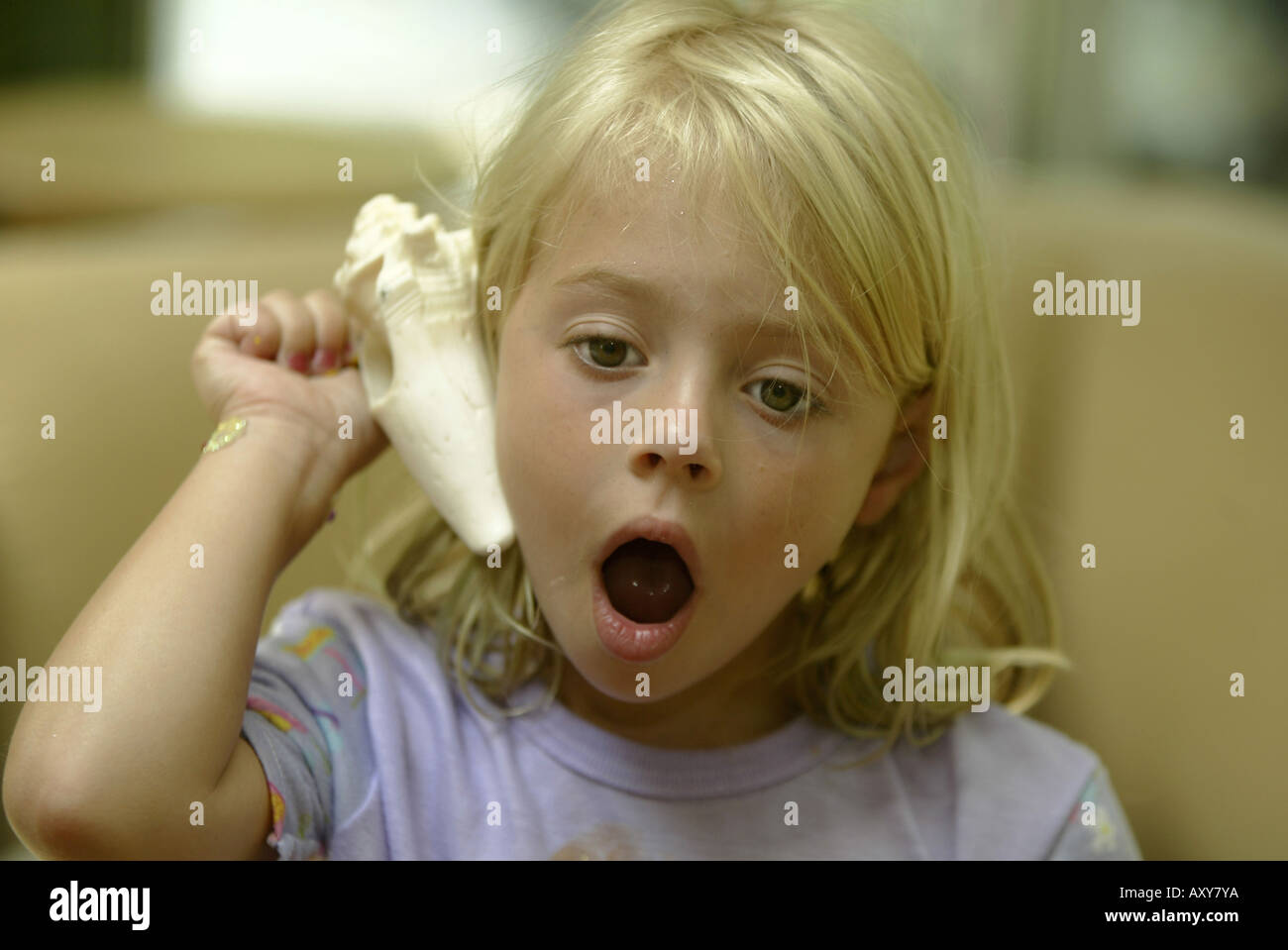 Child listening to sound in a seashell Stock Photo Alamy