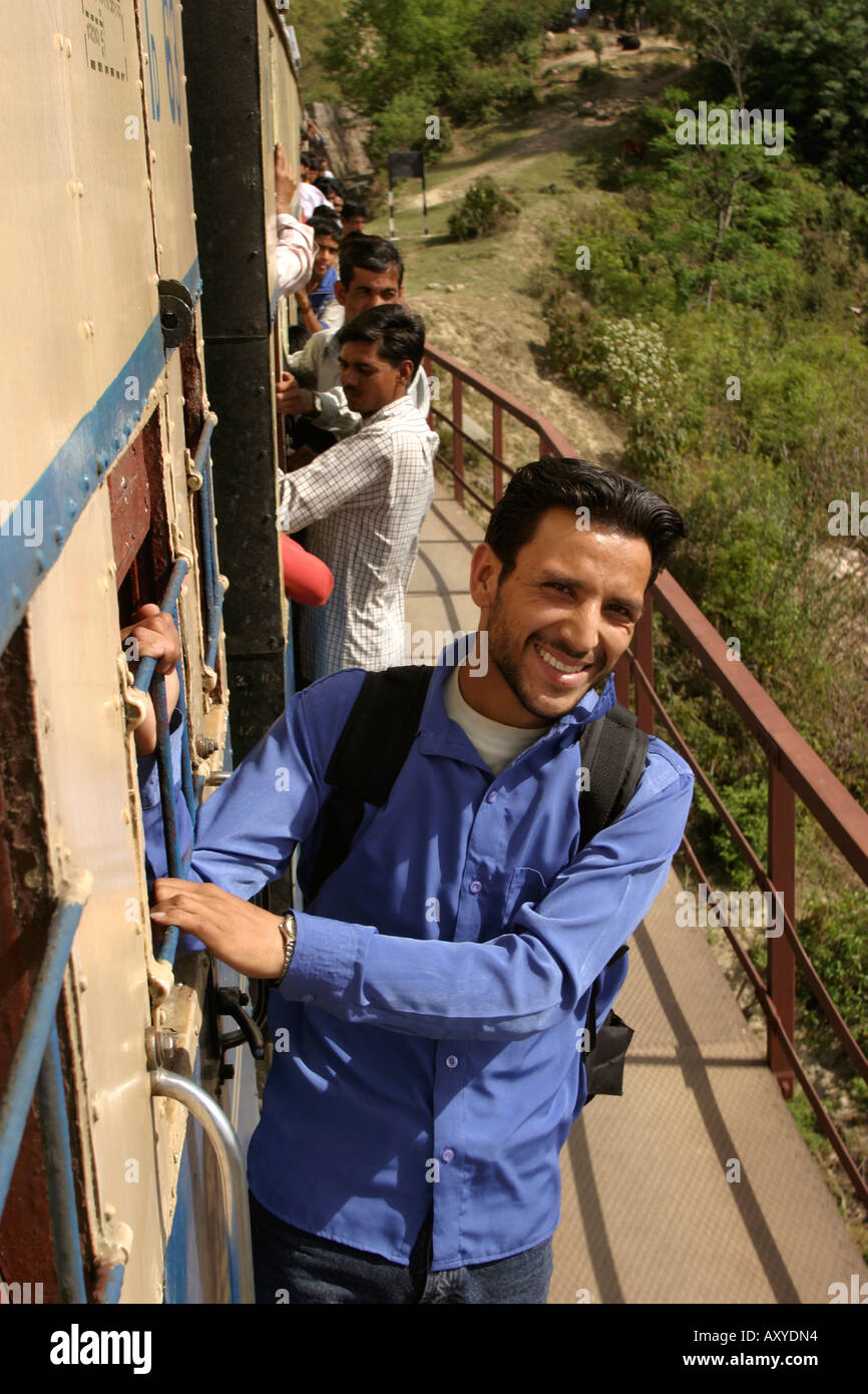 India Himachal Predesh transport passenger hanging onto outside of rural narrow gauge train Stock Photo
