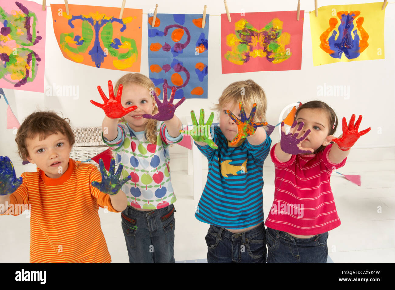 four children hold up their hands which are covered in paint from ...
