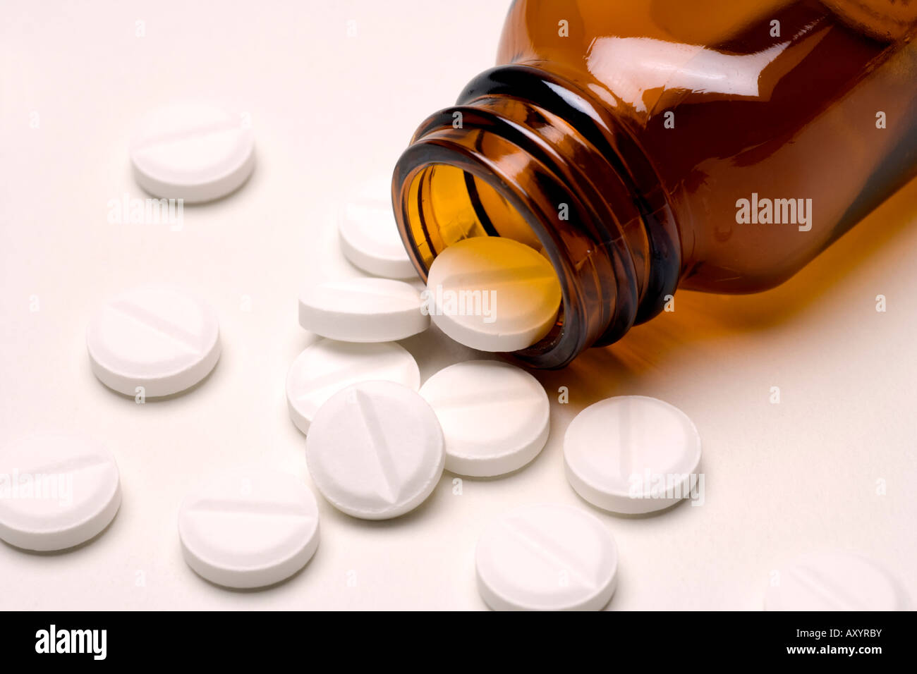 Pills drugs or tablets spilling out of a brown glass medicine bottle aspirin or paracetamol Stock Photo