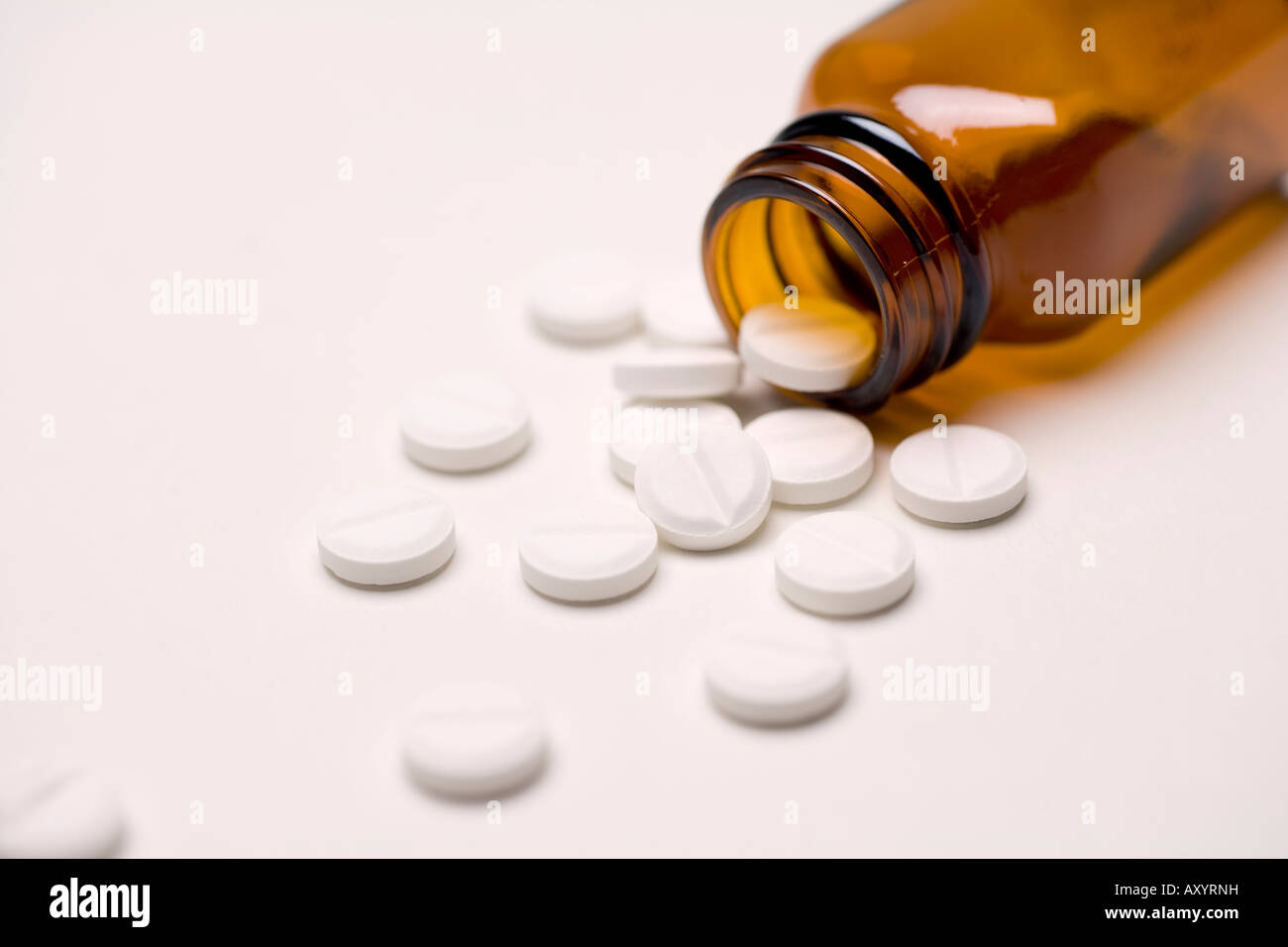 Pills drugs or tablets spilling out of a brown glass medicine bottle aspirin or paracetamol painkillers Stock Photo