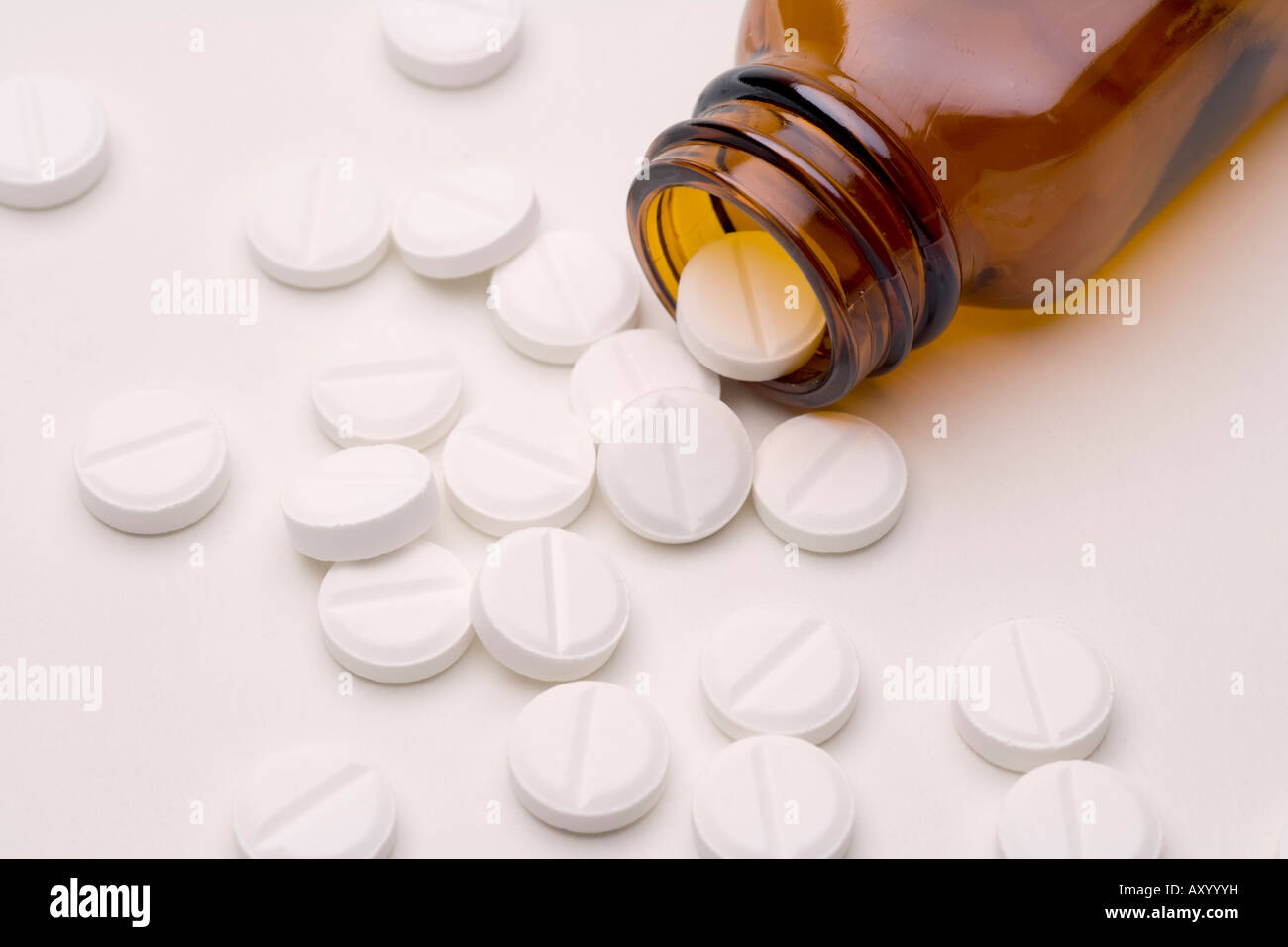 Pills drugs or tablets spilling out of a brown glass medicine bottle aspirin or paracetamol Stock Photo
